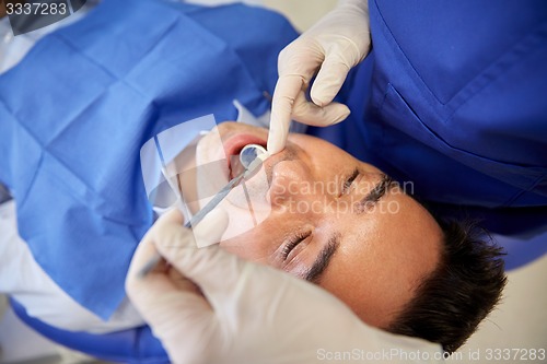 Image of close up of dentist checking male patient teeth