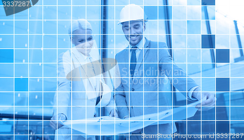 Image of smiling business people in helmets with blueprint