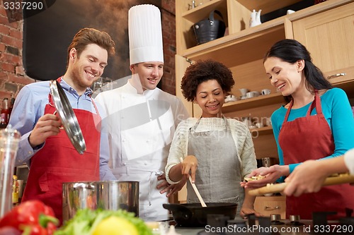 Image of happy friends and chef cook cooking in kitchen