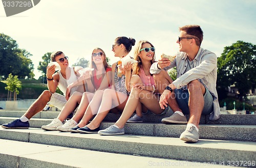 Image of group of smiling friends sitting on city square