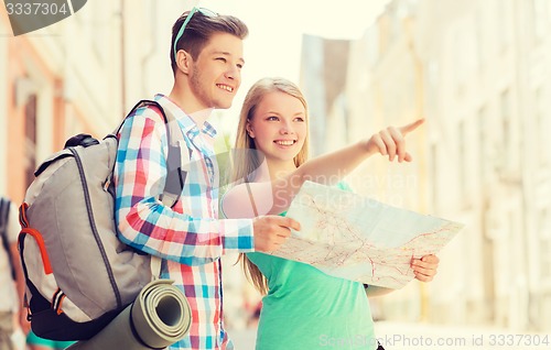 Image of smiling couple with map and backpack in city