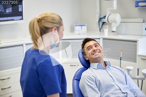 Image of happy female dentist with man patient at clinic