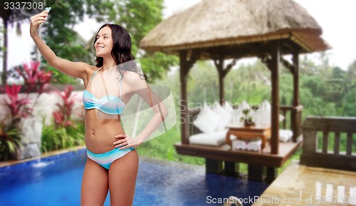 Image of woman in swimsuit taking selfie with smatphone