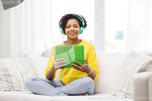 Image of happy african woman with tablet pc and headphones
