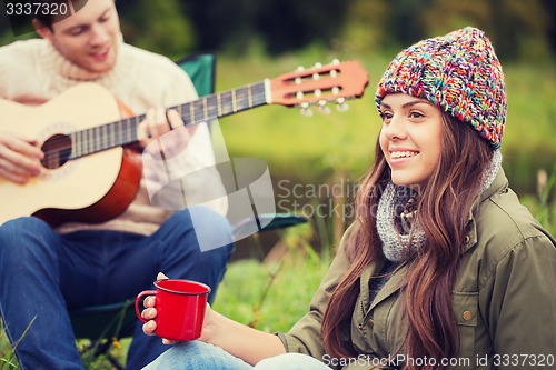 Image of smiling couple with guitar in camping