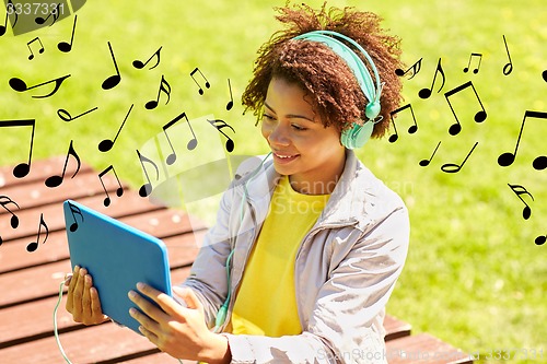 Image of happy african woman in headphones with tablet pc