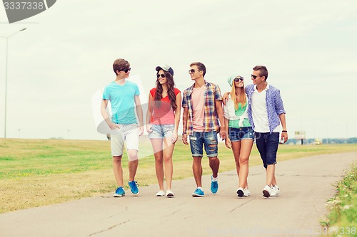 Image of group of smiling teenagers walking outdoors