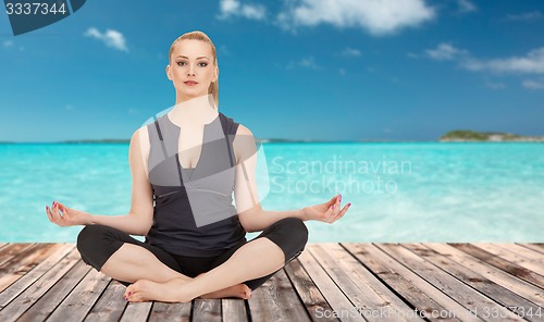 Image of happy young woman meditating in yoga lotus pose