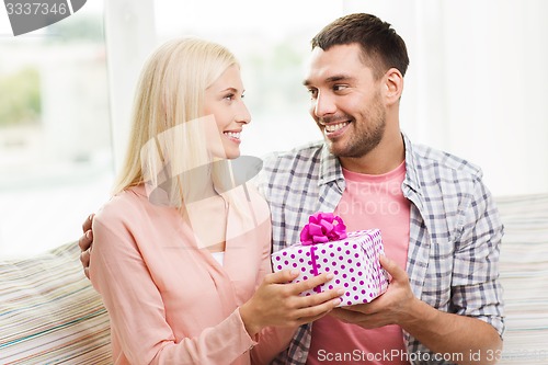 Image of happy man giving woman gift box at home