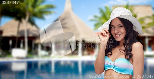 Image of happy woman in swimsuit and sun hat on beach