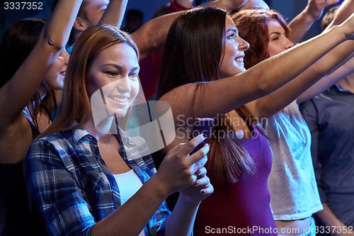 Image of woman with smartphone texting message at concert