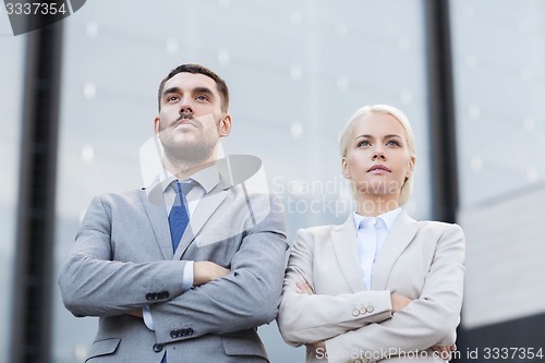 Image of serious businessmen standing over office building