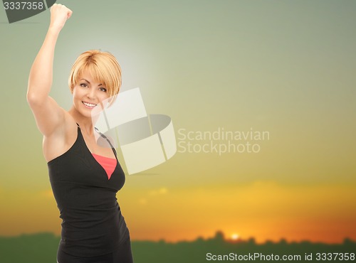 Image of happy woman with raised hand over sunset skyline