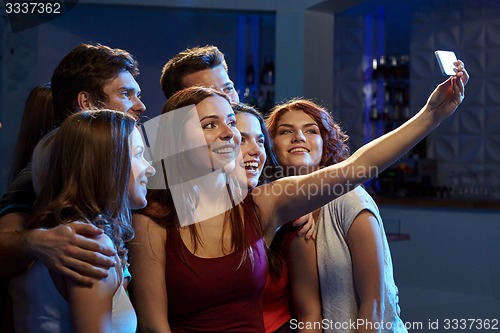 Image of friends with smartphone taking selfie in club