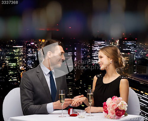 Image of man proposing to his girlfriend at restaurant