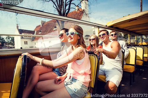 Image of group of smiling friends traveling by tour bus