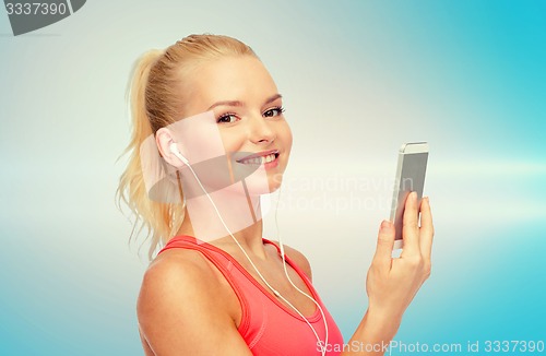 Image of smiling sporty woman with smartphone and earphones