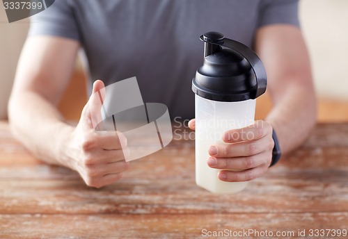 Image of man with protein shake bottle showing thumbs up