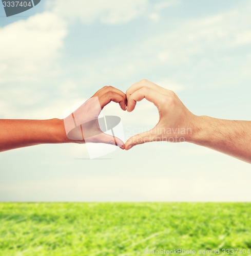 Image of woman and man hands showing heart shape