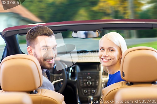Image of happy couple driving in cabriolet car over city