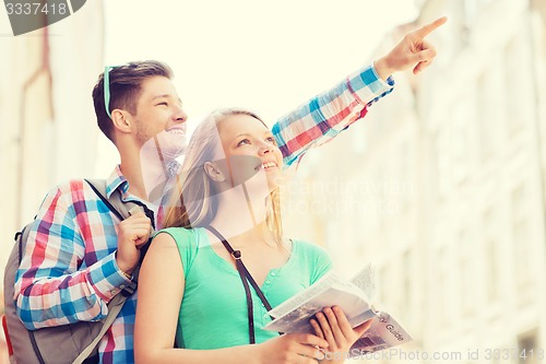 Image of smiling couple with city guide and backpack