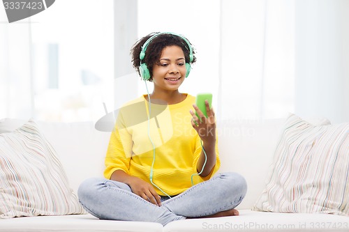 Image of happy african woman with smartphone and headphones