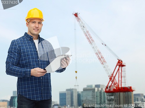 Image of smiling male builder in helmet with clipboard