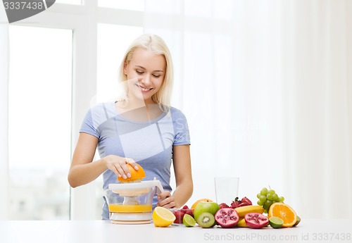 Image of smiling woman squeezing fruit juice at home