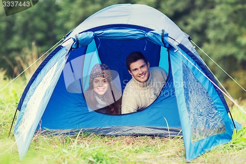 Image of smiling couple of tourists looking out from tent