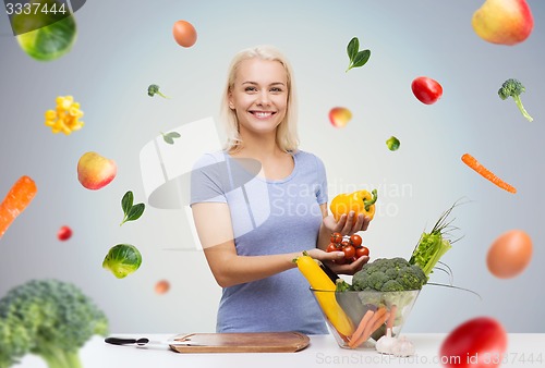 Image of smiling young woman cooking vegetables at home