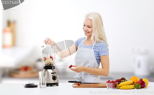 Image of smiling woman with blender preparing shake