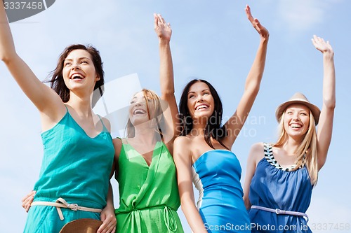 Image of girls walking on the beach and waivng hands