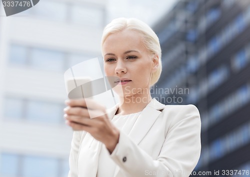 Image of serious businesswoman with smartphone outdoors
