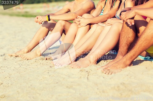 Image of close up of friends sitting on summer beach