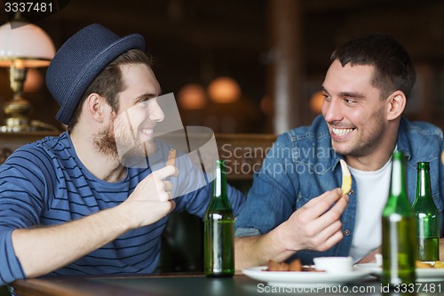 Image of happy male friends drinking beer at bar or pub