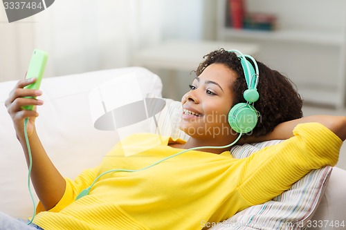 Image of happy african woman with smartphone and headphones