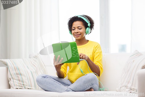 Image of happy african woman with tablet pc and headphones