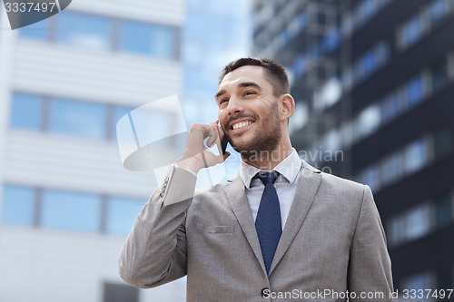 Image of smiling businessman with smartphone outdoors