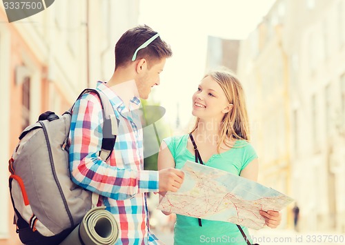 Image of smiling couple with map and backpack in city