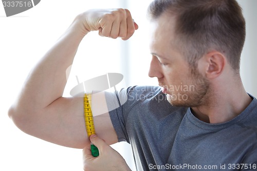 Image of close up of male hands with tape measuring bicep