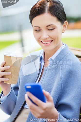 Image of smiling woman with coffee and smartphone