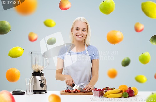Image of smiling woman with blender preparing fruit shake