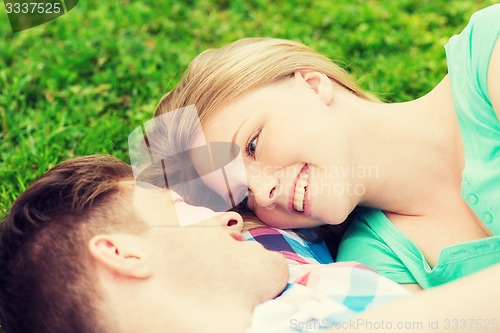 Image of smiling couple lying on grass in park