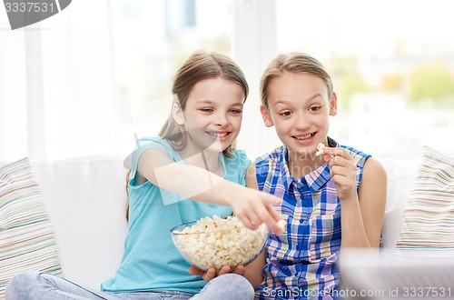 Image of happy girls with popcorn watching tv at home