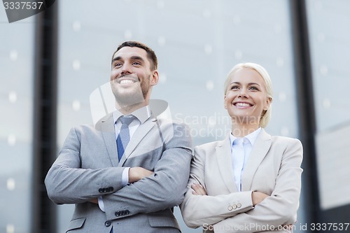 Image of smiling businessmen standing over office building