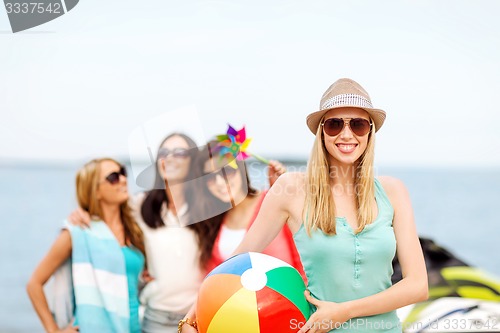 Image of girl with ball and friends on the beach