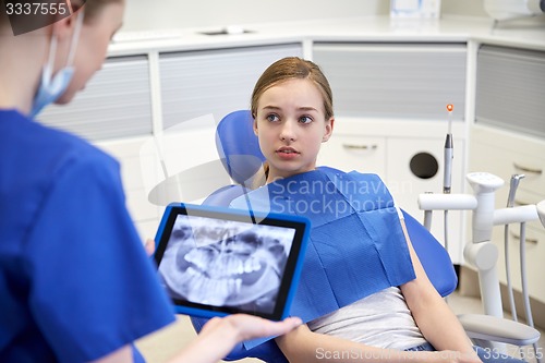 Image of dentist showing x-ray on tablet pc to patient girl