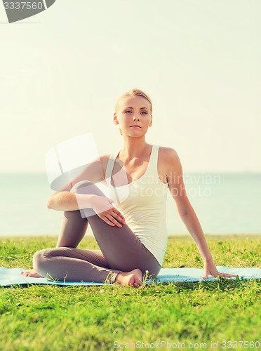 Image of smiling woman making yoga exercises outdoors