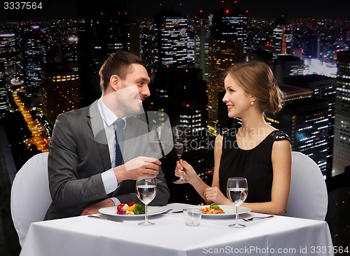 Image of smiling couple eating main course at restaurant