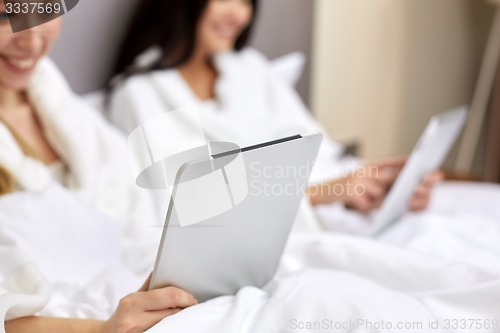 Image of happy women in bathrobes with tablet pc at hotel